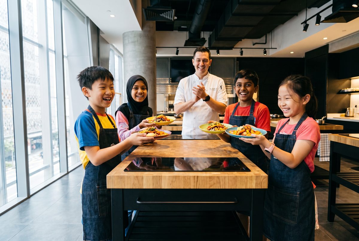 Young chefs proudly holding up the dishes they made at the kids holiday camp in Singapore