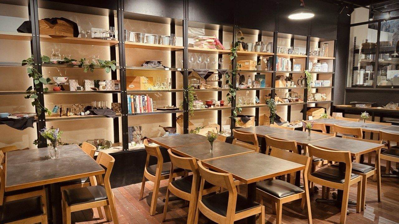 The dedicated dining area at D'Open Kitchen Singapore, with wooden tables and shelves of glassware